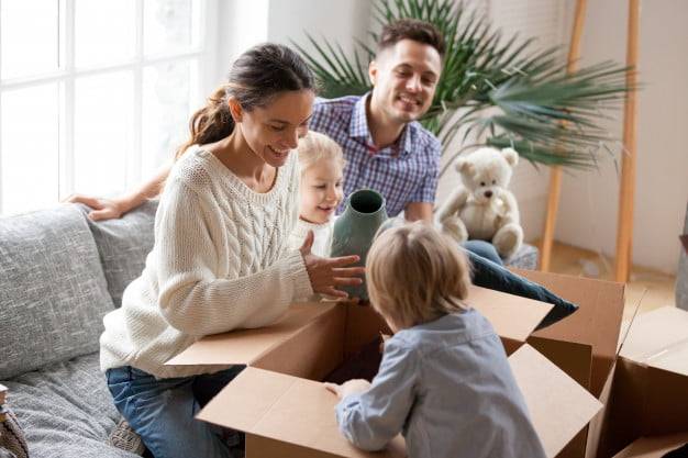 Familia feliz con niños desempacando cajas