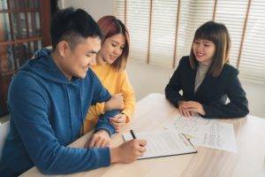 Feliz pareja joven asiática con agente inmobiliario